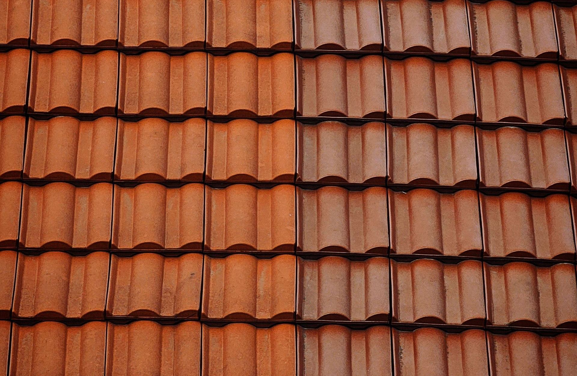 Detailed view of classic red clay roof tiles under a clear blue sky.